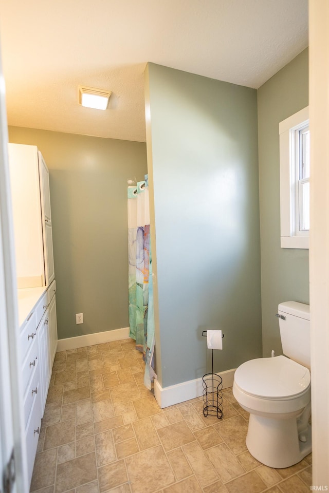 full bathroom featuring curtained shower, baseboards, and toilet