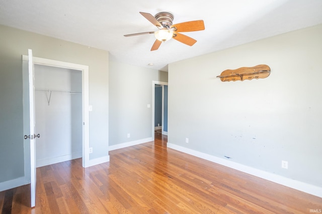 unfurnished bedroom with ceiling fan, a closet, wood finished floors, and baseboards