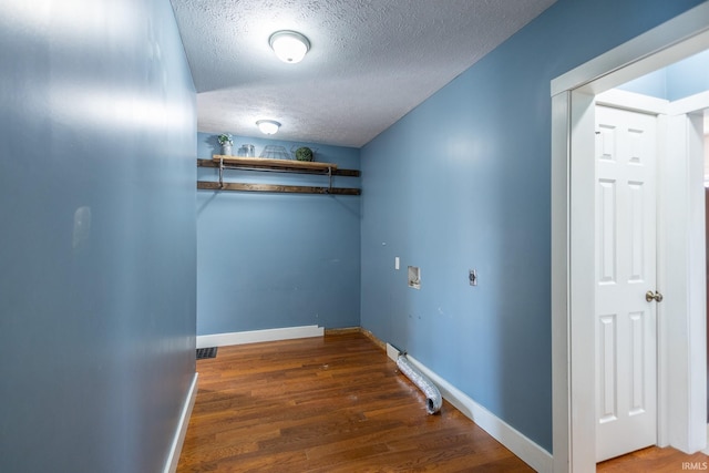 interior space featuring a textured ceiling, laundry area, washer hookup, wood finished floors, and baseboards