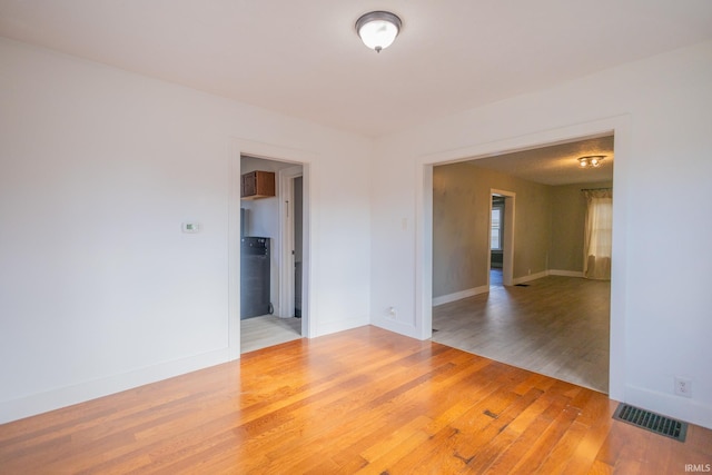 empty room with baseboards, visible vents, and wood finished floors