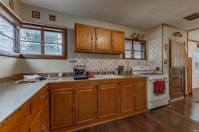 kitchen with a sink, visible vents, white gas range oven, brown cabinetry, and dark wood finished floors