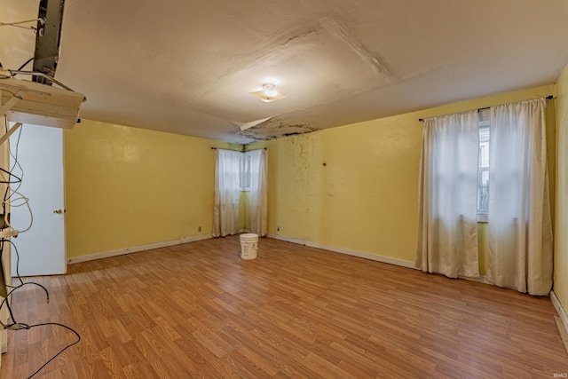 spare room with baseboards and wood finished floors