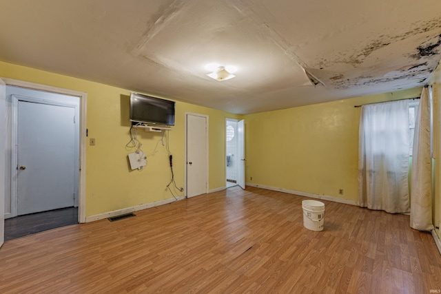 unfurnished room with light wood-type flooring, visible vents, and baseboards