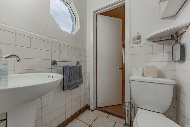 half bathroom featuring toilet, tile patterned flooring, and tile walls