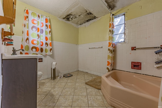 full bathroom featuring toilet, a wainscoted wall, tile patterned flooring, vanity, and tile walls