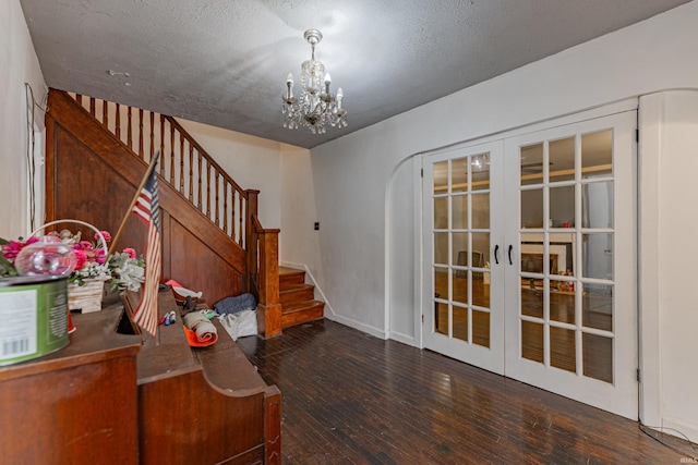 foyer entrance featuring a textured ceiling, french doors, stairway, wood-type flooring, and an inviting chandelier