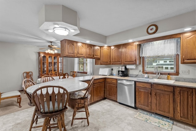 kitchen featuring dishwasher, brown cabinets, a peninsula, light countertops, and a sink