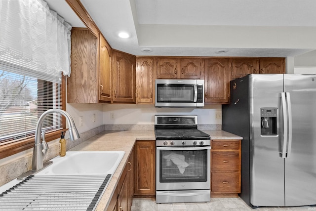 kitchen with stainless steel appliances, light countertops, brown cabinets, and a sink