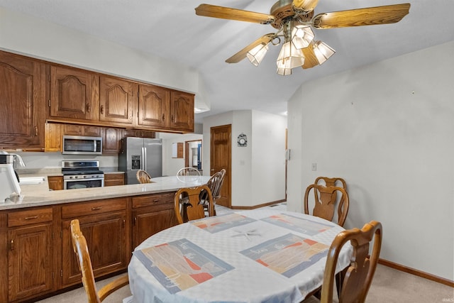 dining area with light carpet, a ceiling fan, and baseboards