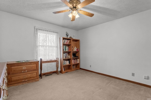 interior space featuring light colored carpet, ceiling fan, a textured ceiling, and baseboards