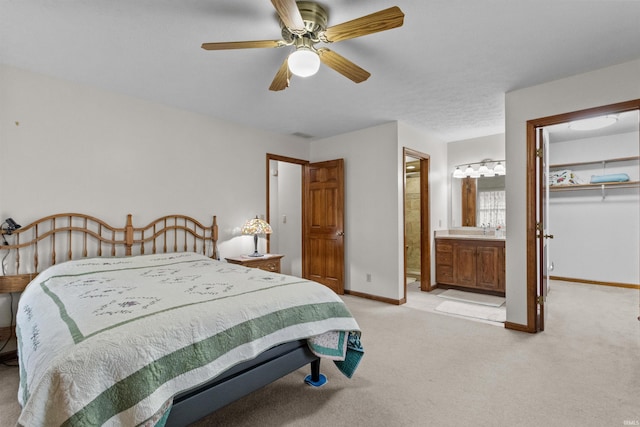 bedroom with light colored carpet, a sink, baseboards, a closet, and a walk in closet