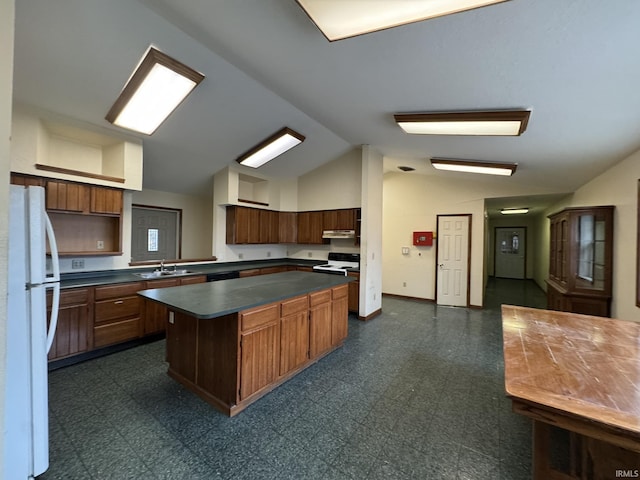 kitchen featuring dark floors, range with electric stovetop, freestanding refrigerator, a center island, and dark countertops