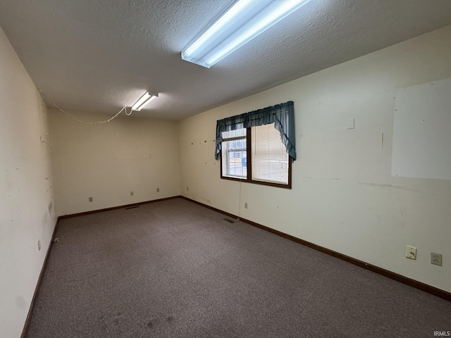 carpeted empty room with a textured ceiling, visible vents, and baseboards