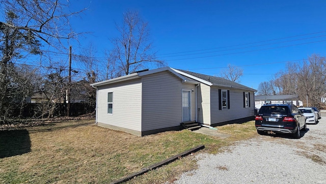 view of property exterior with entry steps, a yard, and an outdoor structure