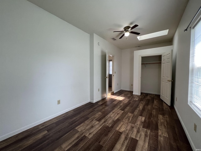 unfurnished bedroom featuring a skylight, baseboards, visible vents, dark wood-type flooring, and multiple windows