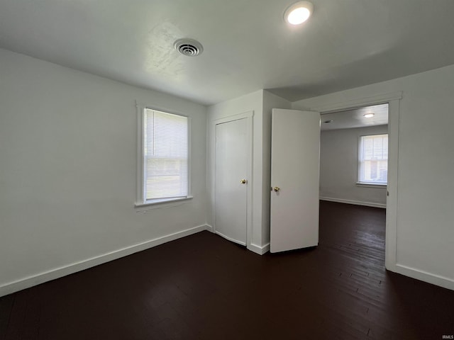 spare room with dark wood-style floors, baseboards, and visible vents