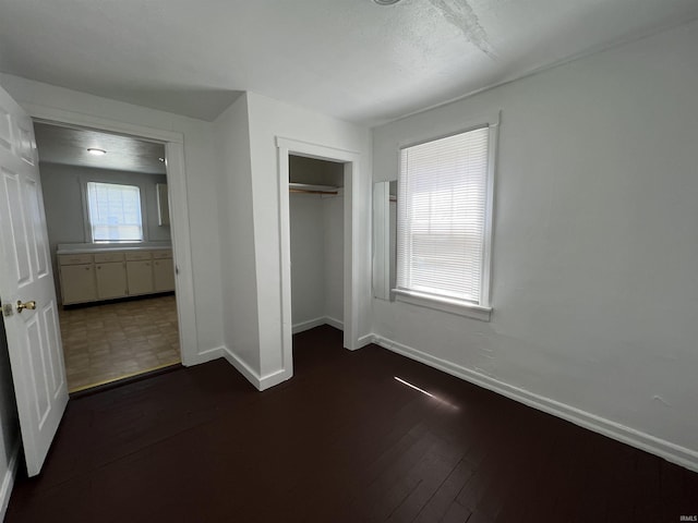 unfurnished bedroom with a closet, dark wood finished floors, and baseboards