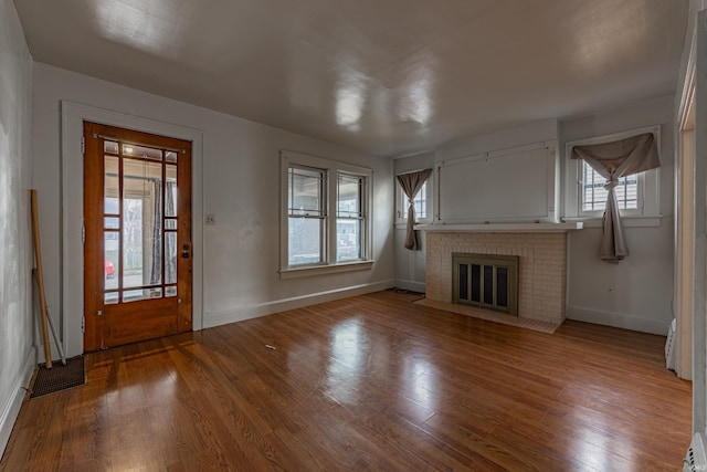 unfurnished living room with a fireplace, baseboards, and wood finished floors