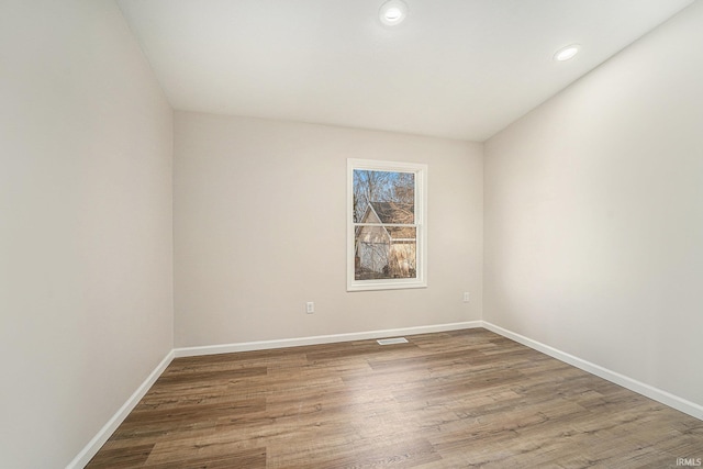 unfurnished room with baseboards, visible vents, wood finished floors, and recessed lighting