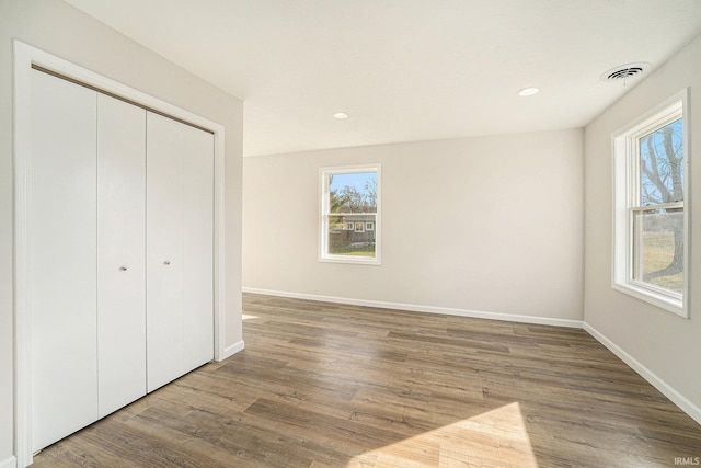 unfurnished bedroom featuring visible vents, a closet, baseboards, and wood finished floors