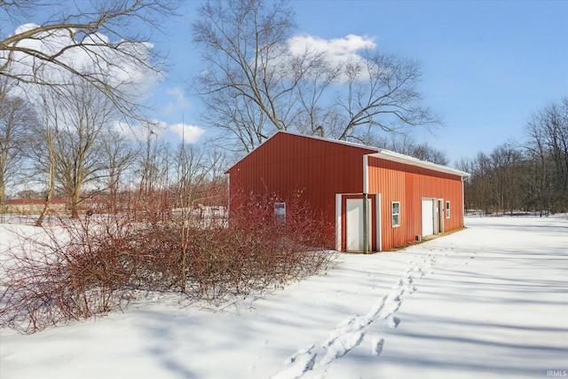 snow covered structure featuring an outbuilding