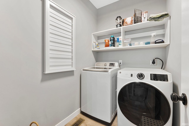 washroom featuring visible vents, light wood-style floors, washing machine and dryer, laundry area, and baseboards