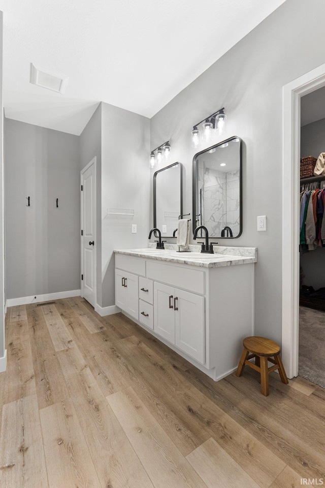 full bathroom featuring a sink, double vanity, a spacious closet, and wood finished floors