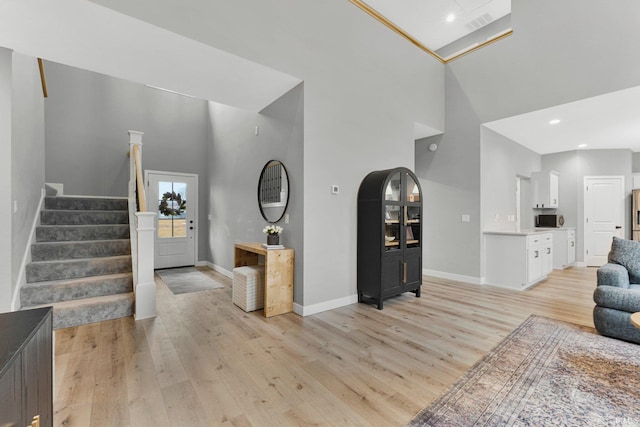 entryway with recessed lighting, a high ceiling, baseboards, light wood-style floors, and stairway