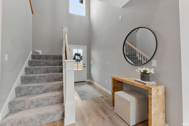 entryway featuring stairway, wood finished floors, a towering ceiling, and baseboards