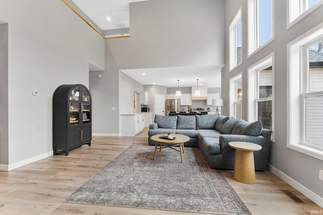 living room with light wood-style flooring, visible vents, and baseboards