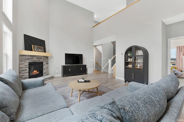 living room with stairs, a high ceiling, a fireplace, and wood finished floors