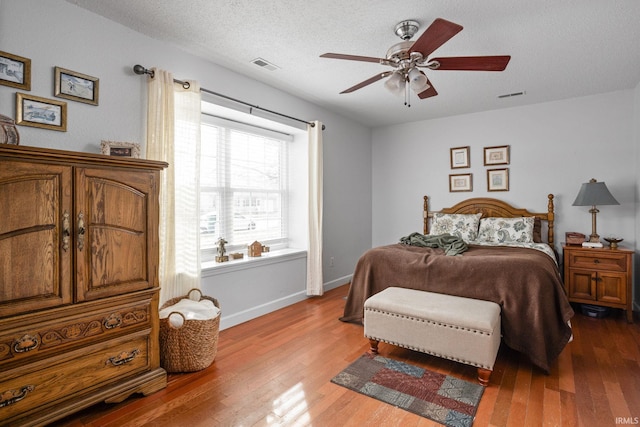 bedroom featuring a textured ceiling, wood finished floors, visible vents, and baseboards