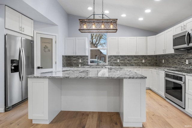 kitchen with light wood finished floors, a kitchen island, appliances with stainless steel finishes, vaulted ceiling, and white cabinetry