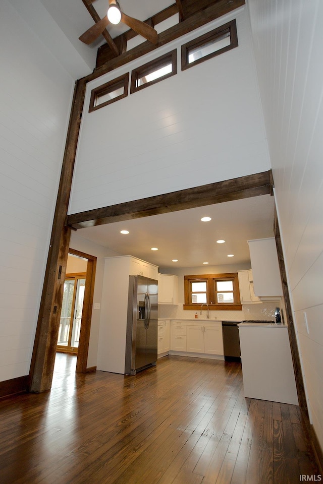 unfurnished living room featuring a ceiling fan, dark wood-style floors, beamed ceiling, a sink, and recessed lighting