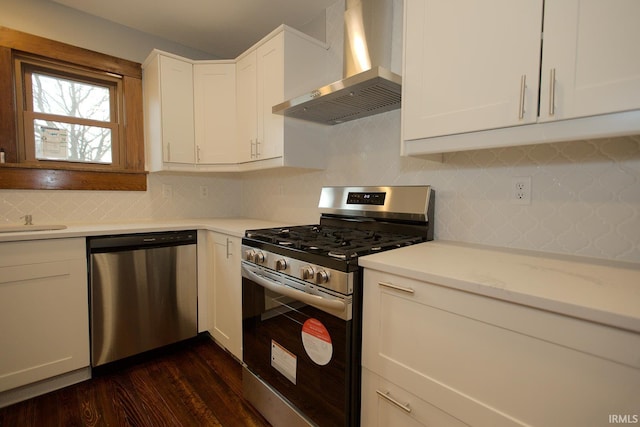 kitchen featuring wall chimney exhaust hood, dark wood-type flooring, white cabinets, and stainless steel appliances