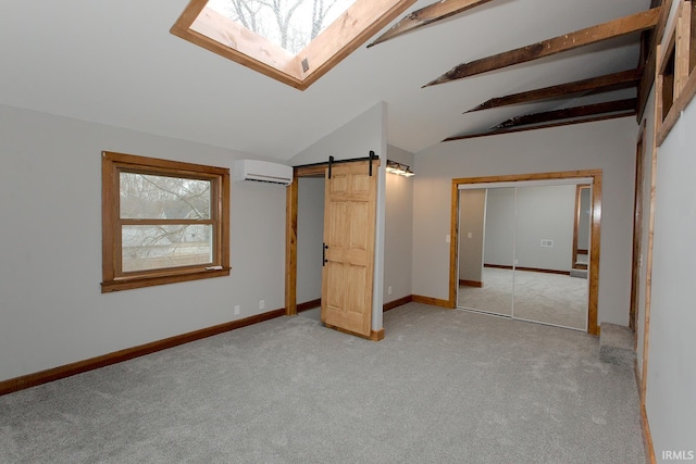 unfurnished bedroom with a barn door, baseboards, lofted ceiling with skylight, an AC wall unit, and carpet floors