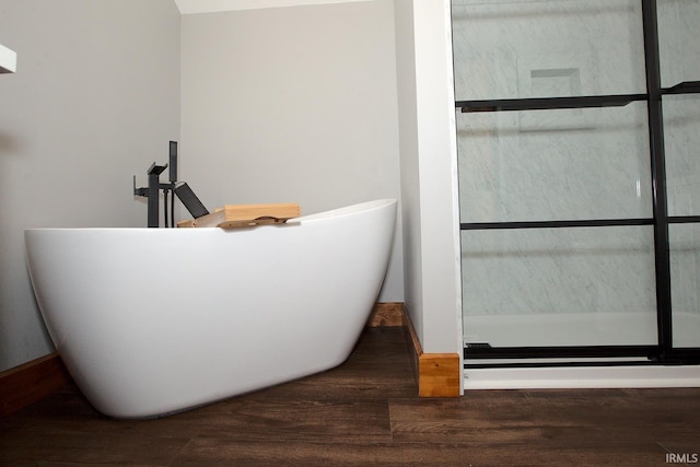 bathroom with a freestanding bath and wood finished floors