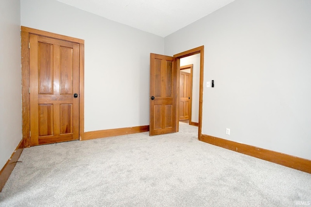 unfurnished bedroom with light colored carpet and baseboards