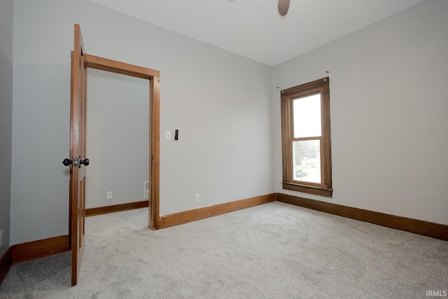 spare room with light carpet, ceiling fan, visible vents, and baseboards