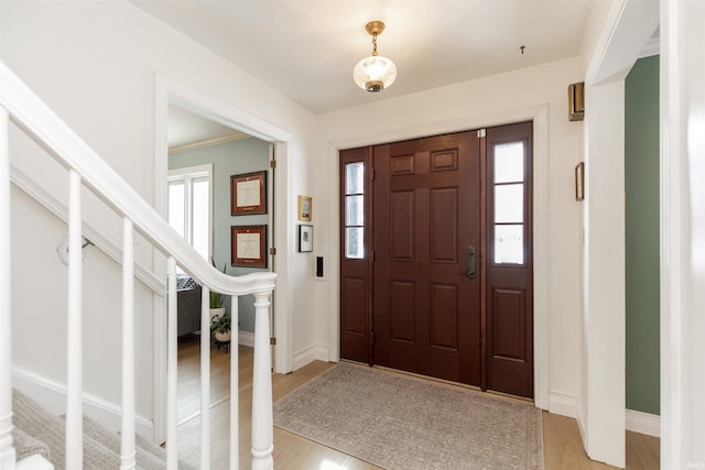 entryway with light wood-style floors, stairs, and baseboards