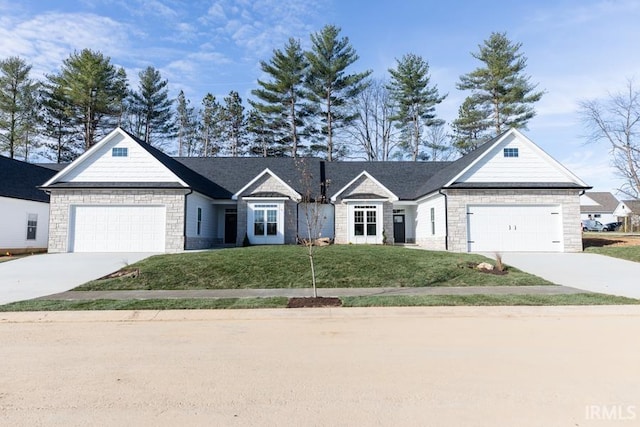 view of front of property with a front yard, stone siding, driveway, and an attached garage