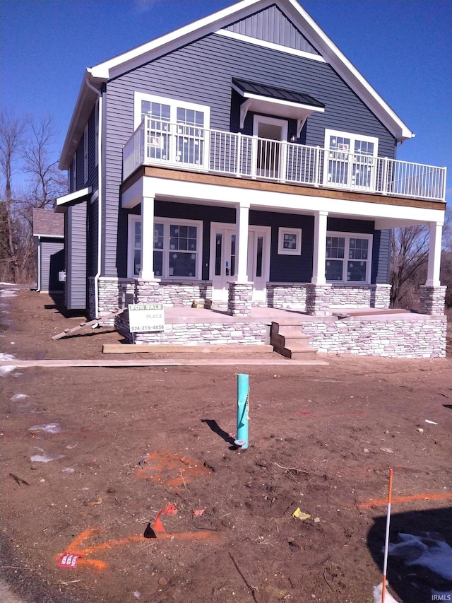 view of front facade with stone siding and a balcony