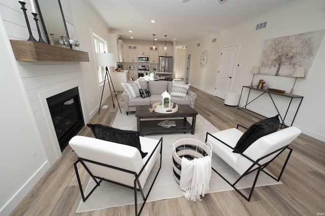 3337 Blarney Dr, South Bend, IN 46628 - living area with light wood-type flooring, baseboards, a glass covered fireplace, recessed lighting, and ornamental molding