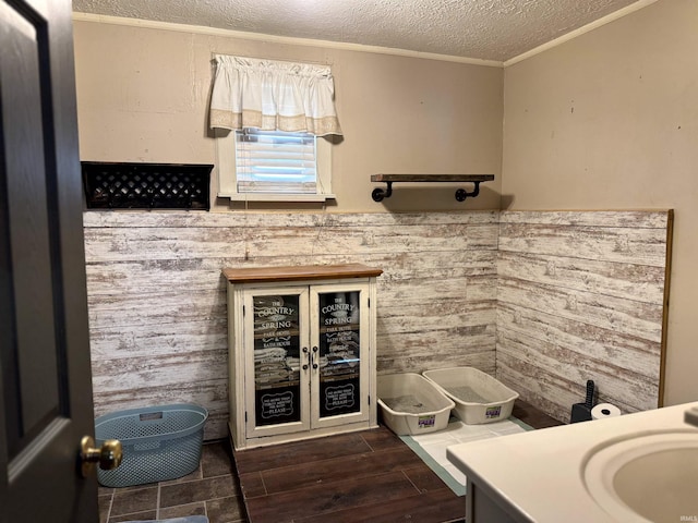 bathroom featuring wainscoting, wood finished floors, crown molding, vanity, and a textured ceiling