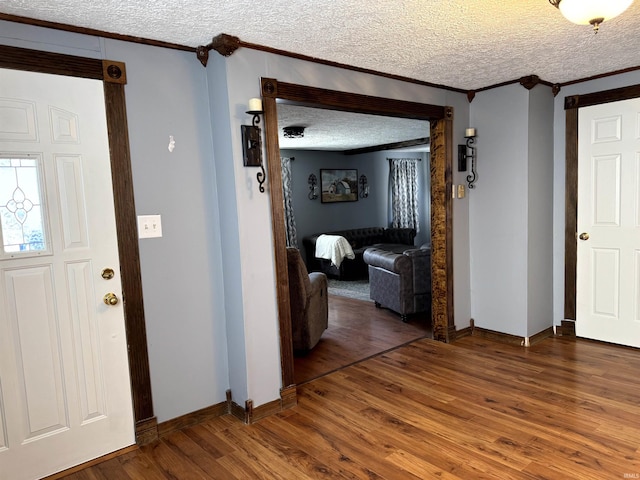 interior space featuring crown molding, a textured ceiling, baseboards, and wood finished floors