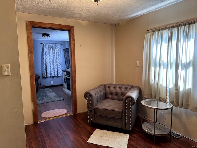 living area with a textured ceiling, wood finished floors, and visible vents