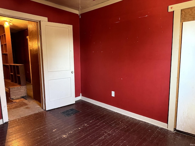 unfurnished room featuring baseboards, visible vents, and hardwood / wood-style floors