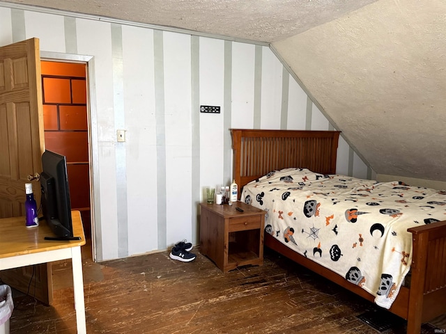 bedroom with vaulted ceiling, hardwood / wood-style floors, and a textured ceiling