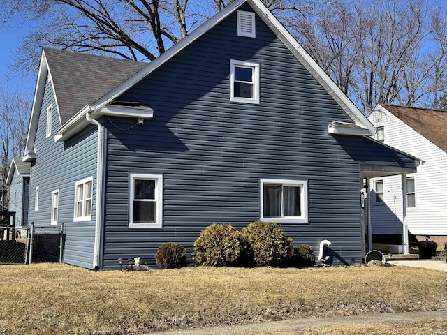 view of property exterior with a shingled roof, a yard, and fence