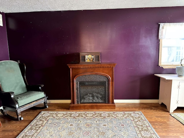 living area featuring a fireplace, baseboards, and wood finished floors